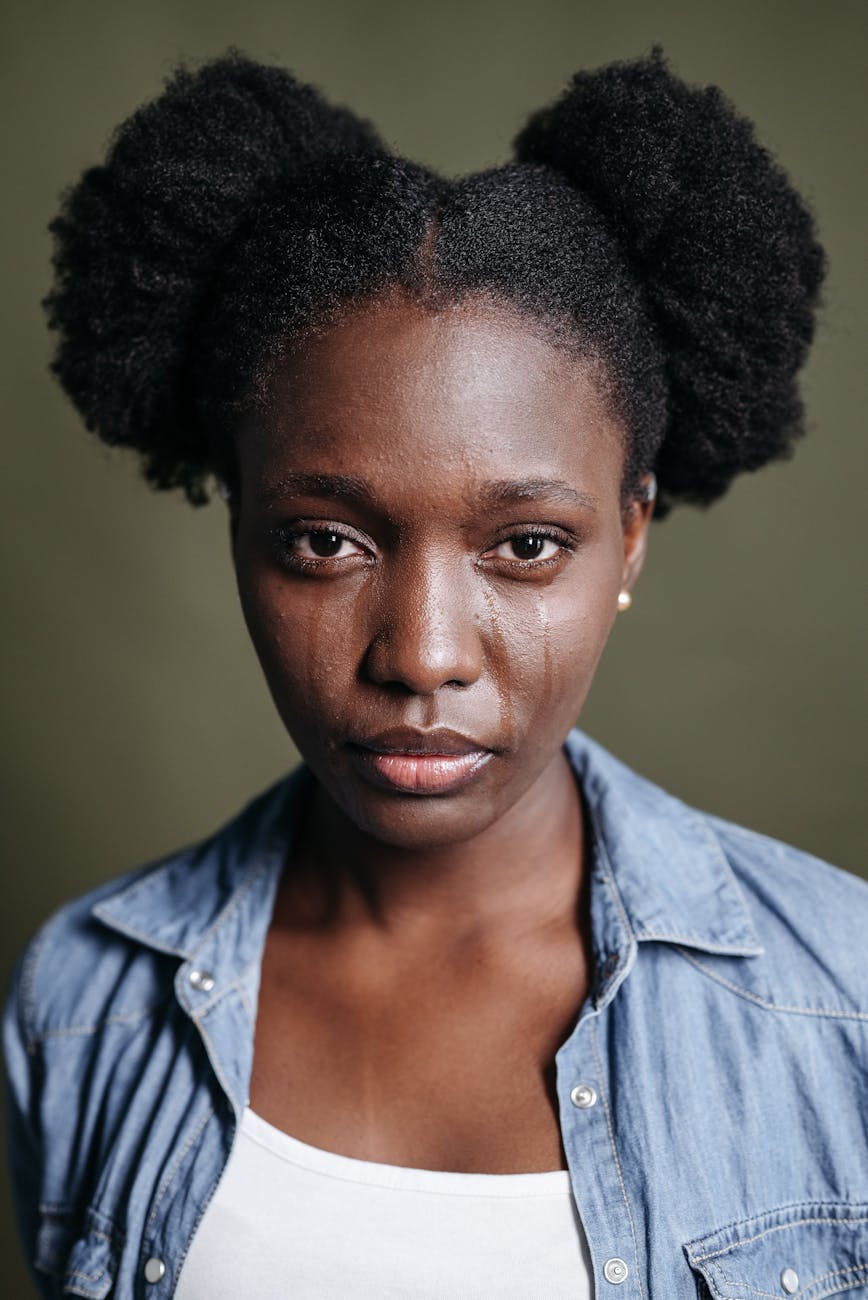 Close-up portrait of a woman with tears on her face, conveying emotion.