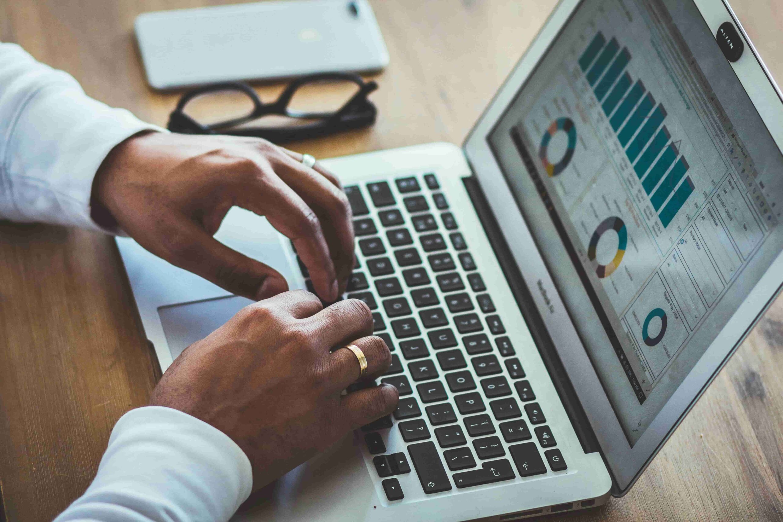 Man typing on a laptop with analytics displayed on the screen, representing data analysis and digital marketing