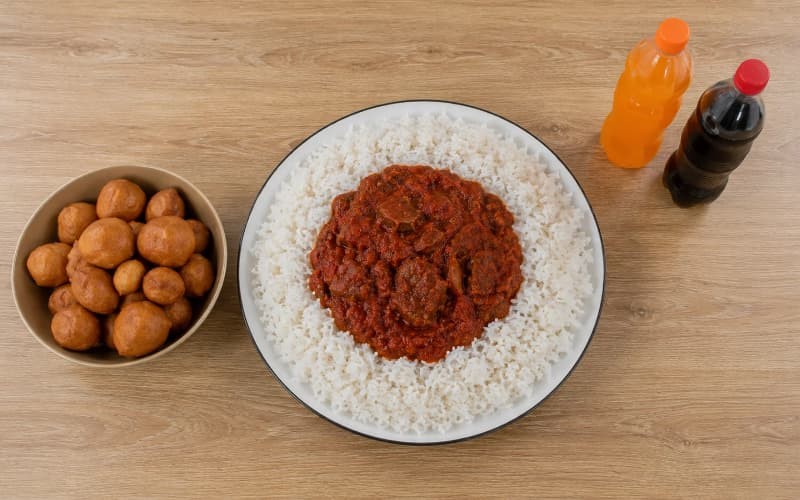 large portion of white rice, soft drinks and fried snacks representing Nigerian foods to eat less of for weight loss